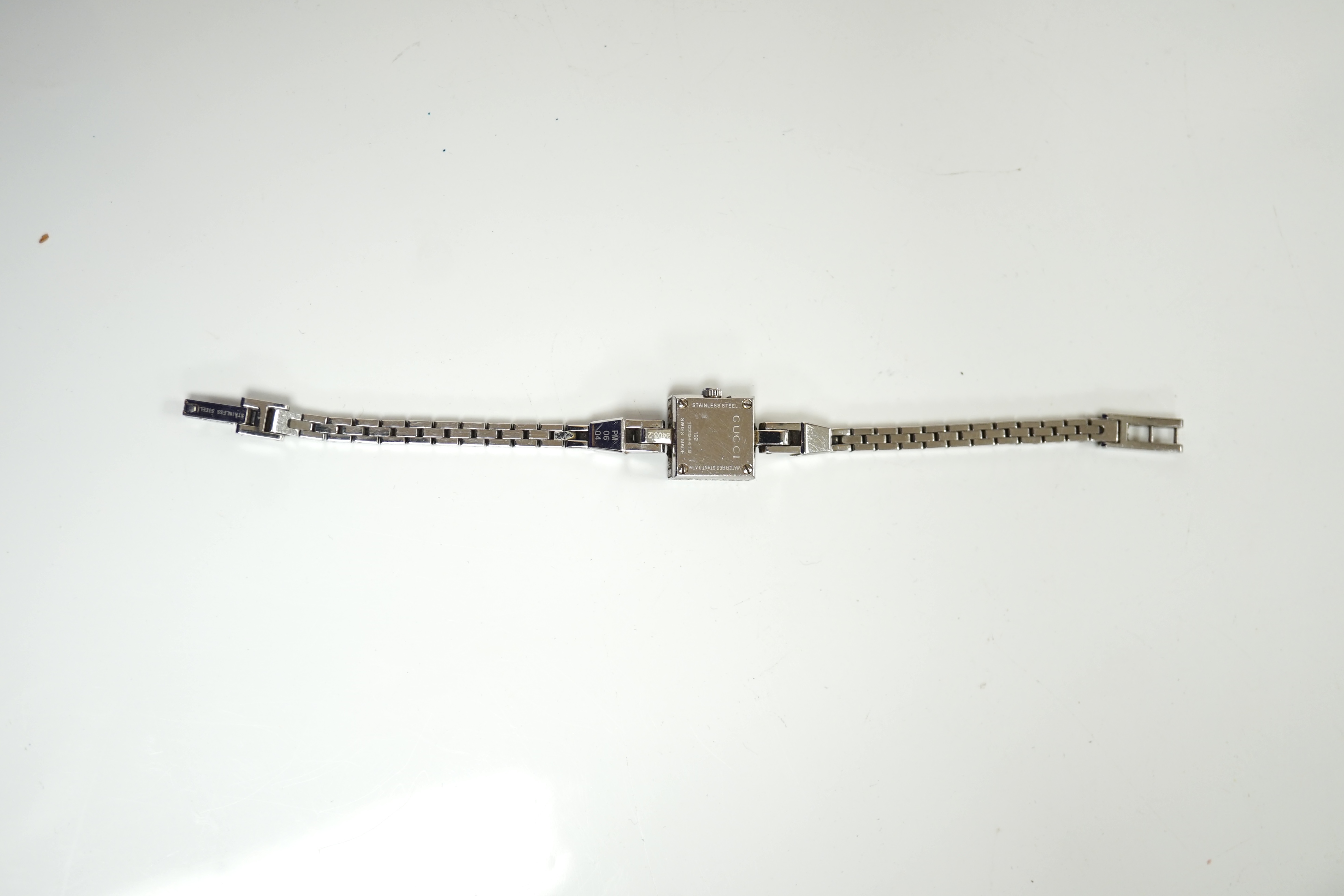 A lady's stainless steel Gucci quartz wrist watch, with G shaped case and diamond chip set bezel, on a stainless steel Gucci bracelet. Condition - fair